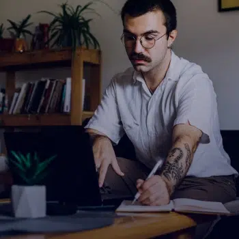persona tomando apuntes frente a un portátil durante una clase online