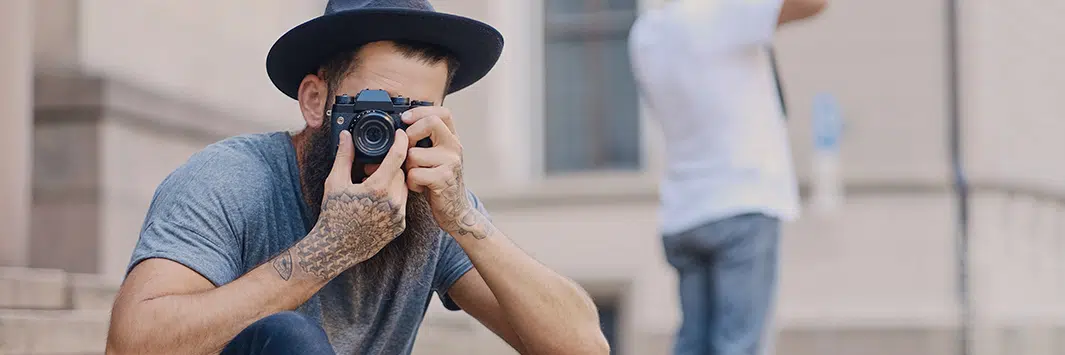 persona con sombrero mirando al frente con una cámara de fotos preparada para fotografiar