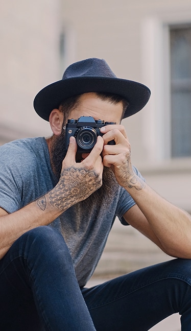 persona con sombrero mirando al frente con una cámara de fotos preparada para fotografiar curso fotografía