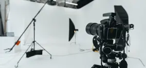 estudio fotográfico con elementos de iluminación, cables y en primer plano una cámara lista para una sesión de fotos