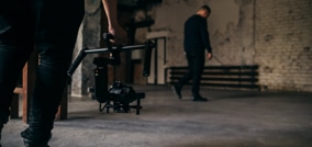 persona sujetando equipo de fotografía con otra de fondo en un set