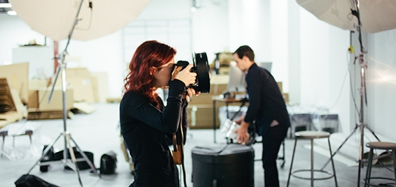 persona con cámara en mano en un estudio de fotografía con iluminación y otro material