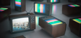 Televisiones antiguas que muestran barras de colores en sus pantallas. En una de ellas se visualiza una ciudad