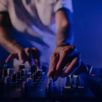 manos de persona mezclando en consola de DJ curso 35 mm