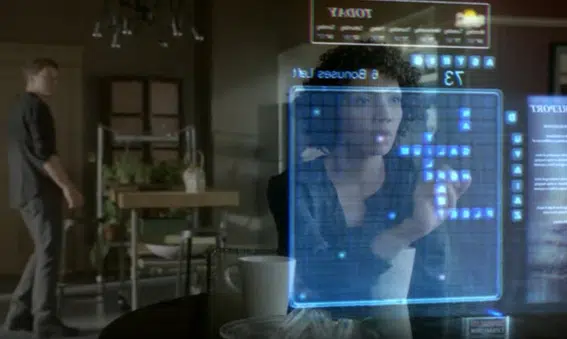 La fotografía muestra la escena de una película en la que se usan efectos especiales para simular un panel de control holográfico con el que interactúa una mujer