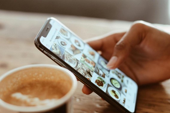 En la imagen, una persona revisa fotograf&iacute;as de platos de comida en la galer&iacute;a de su smartphone