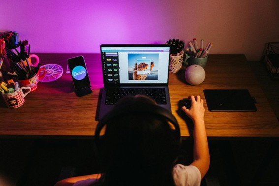 La imagen muestra a una joven de espaldas editando sus fotograf&iacute;as en Canva