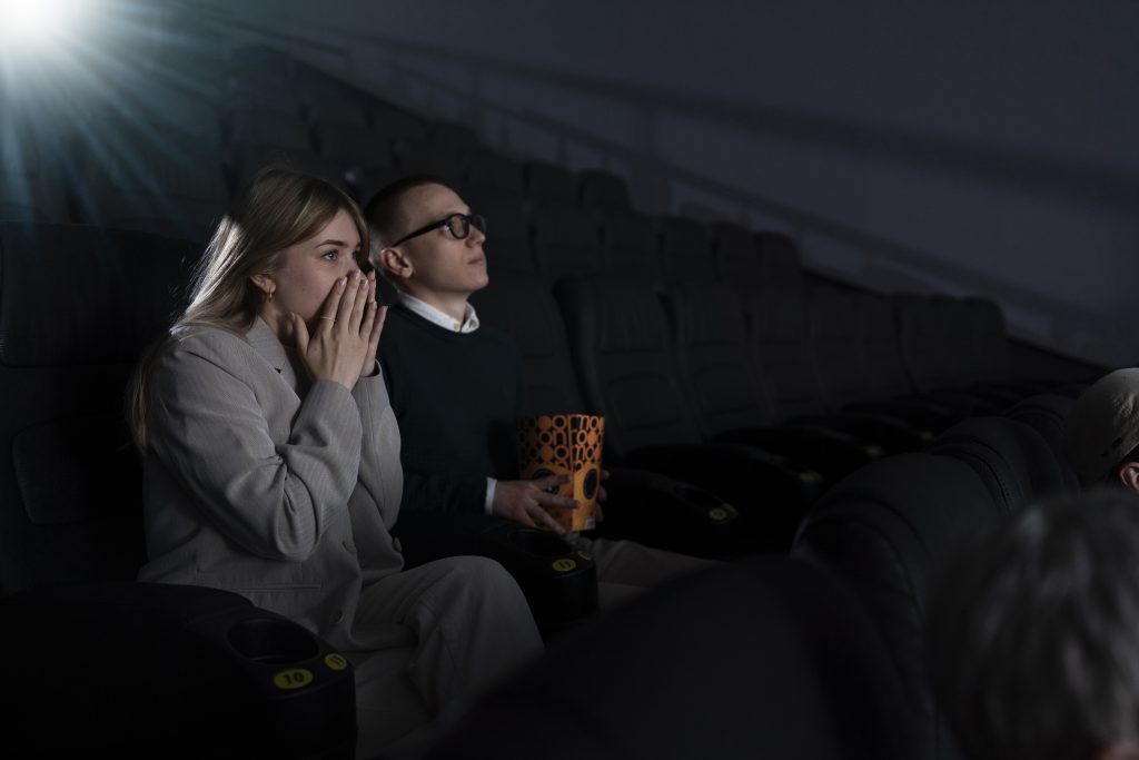 Dos personas sentadas ven una película en una sala de cine